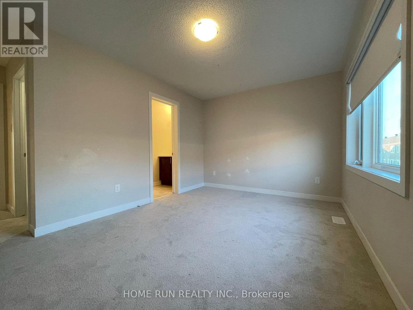 A spacious room with a carpeted floor and a door at the end.