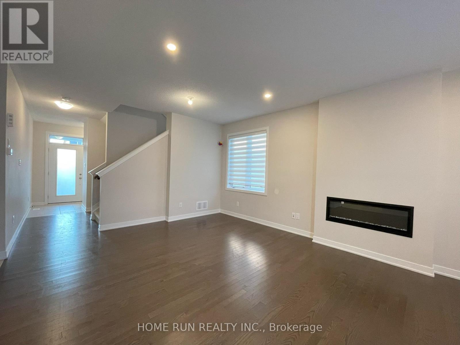 A spacious living room with wood flooring and a fireplace.