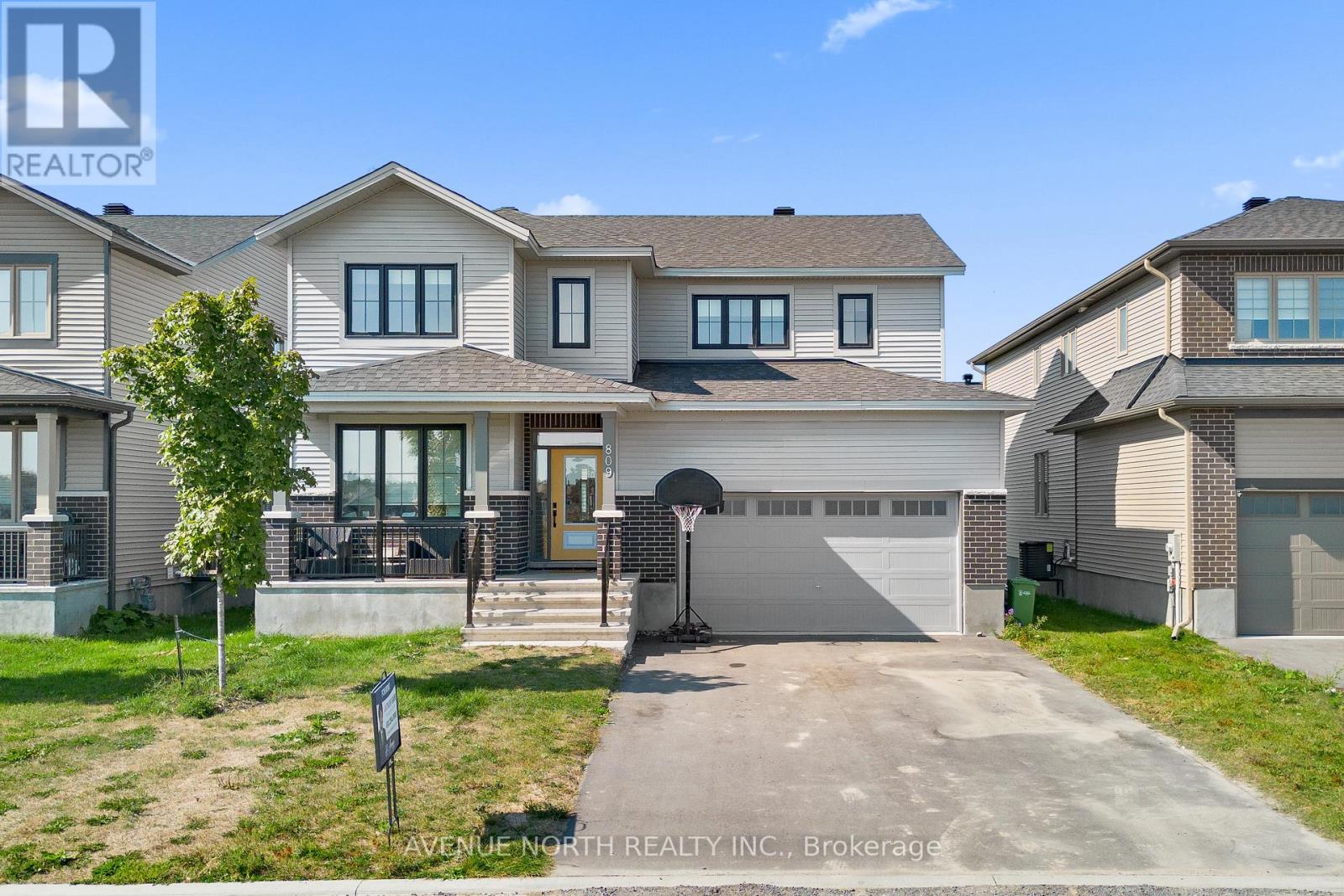 A large, well-maintained house with a driveway and a sign for Avenue North Realty, Brokerage.