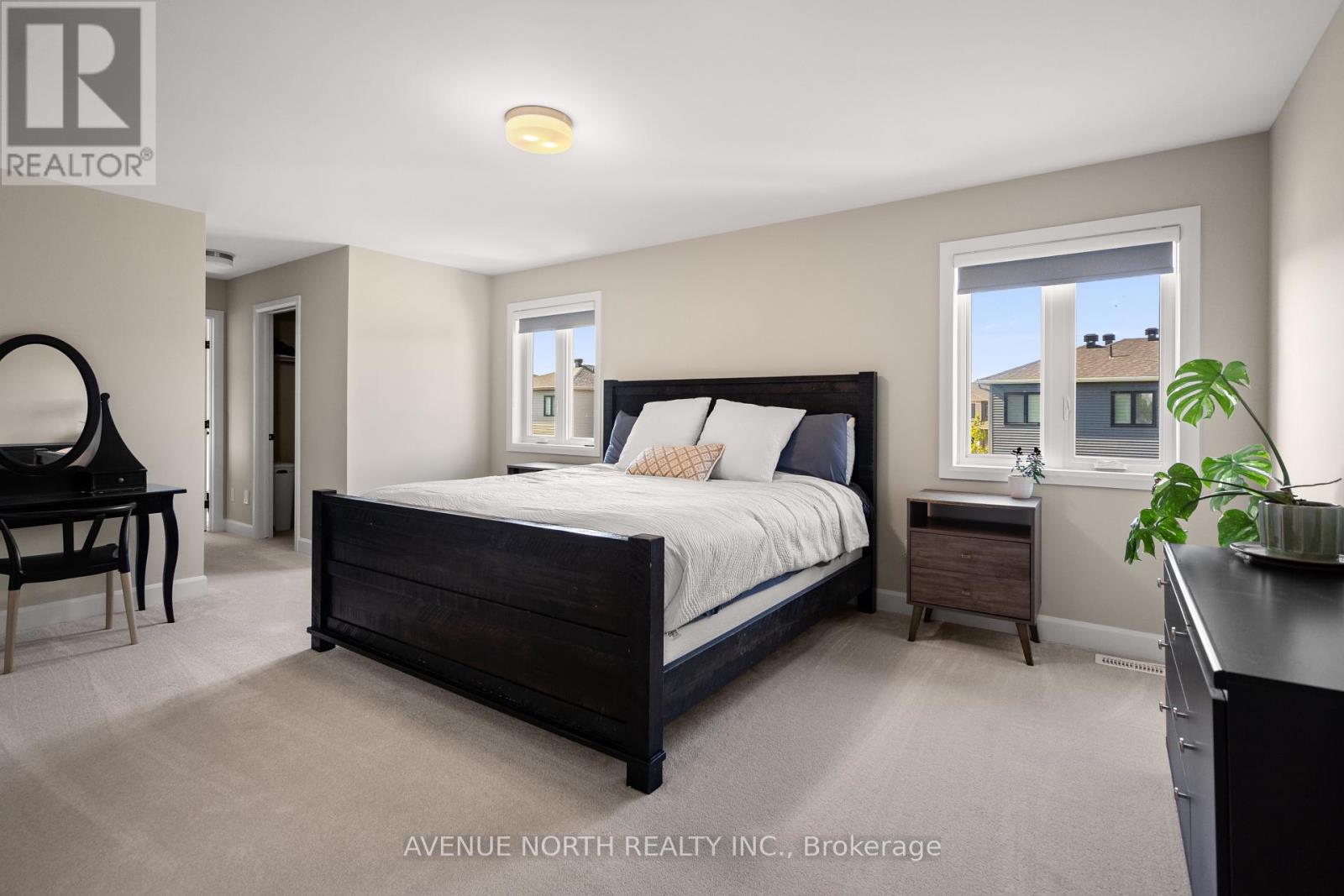 A bedroom with a large bed, a chair, and a window.
