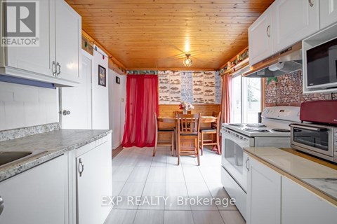 A kitchen with white cabinets and a wooden ceiling.
