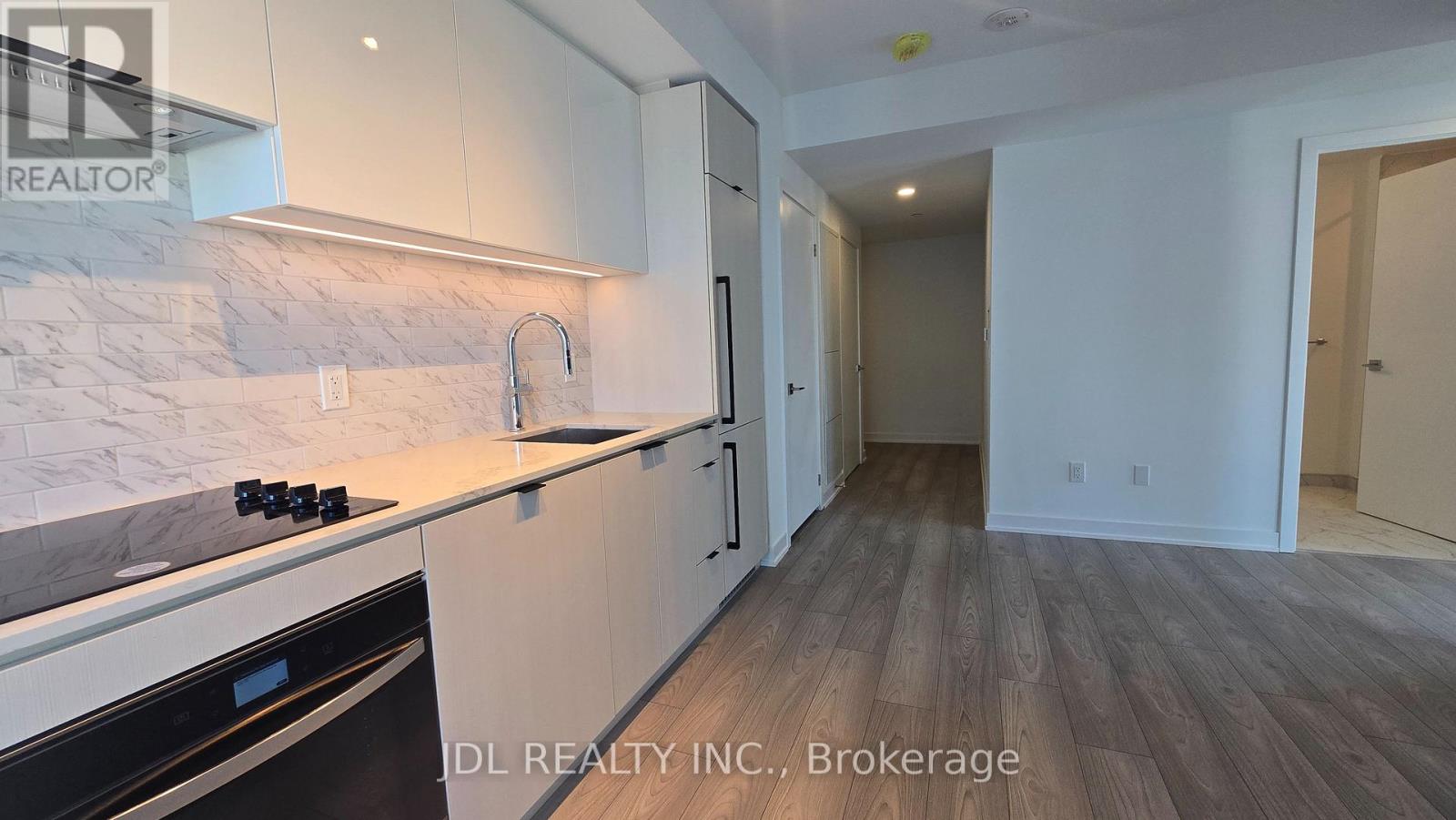 A kitchen with white cabinets and a marble backsplash.