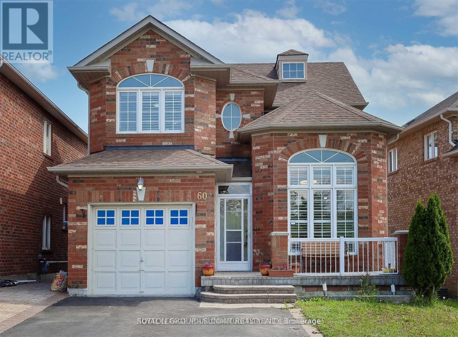 A brick house with a white garage door and a balcony.