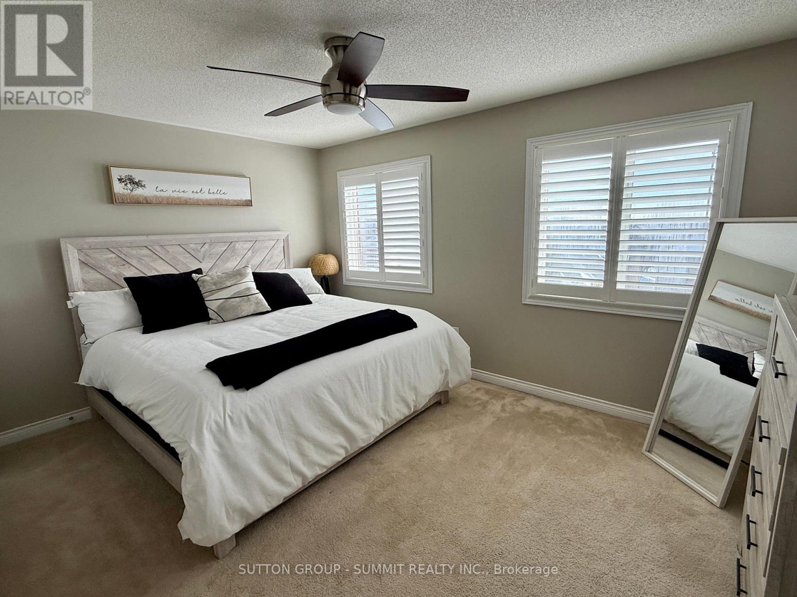 A bedroom with a white bed and a ceiling fan.
