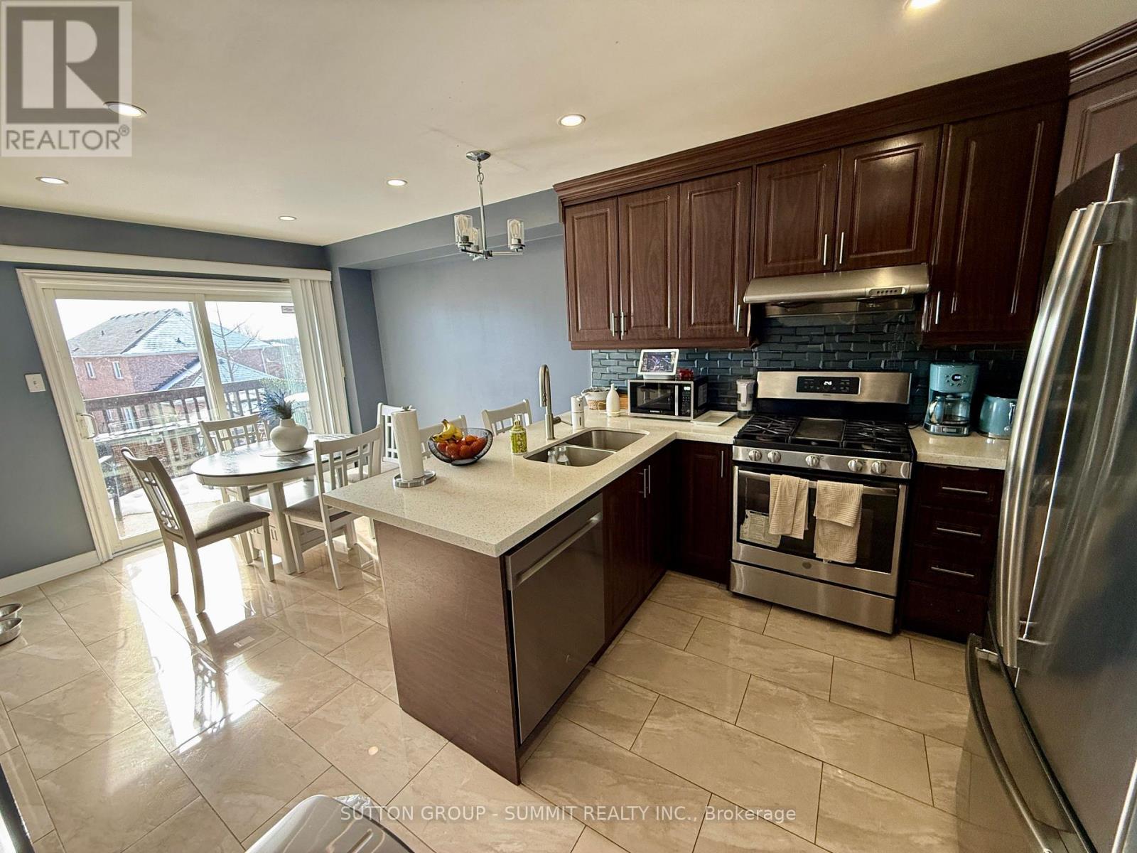 A kitchen with a refrigerator, sink, and stove.