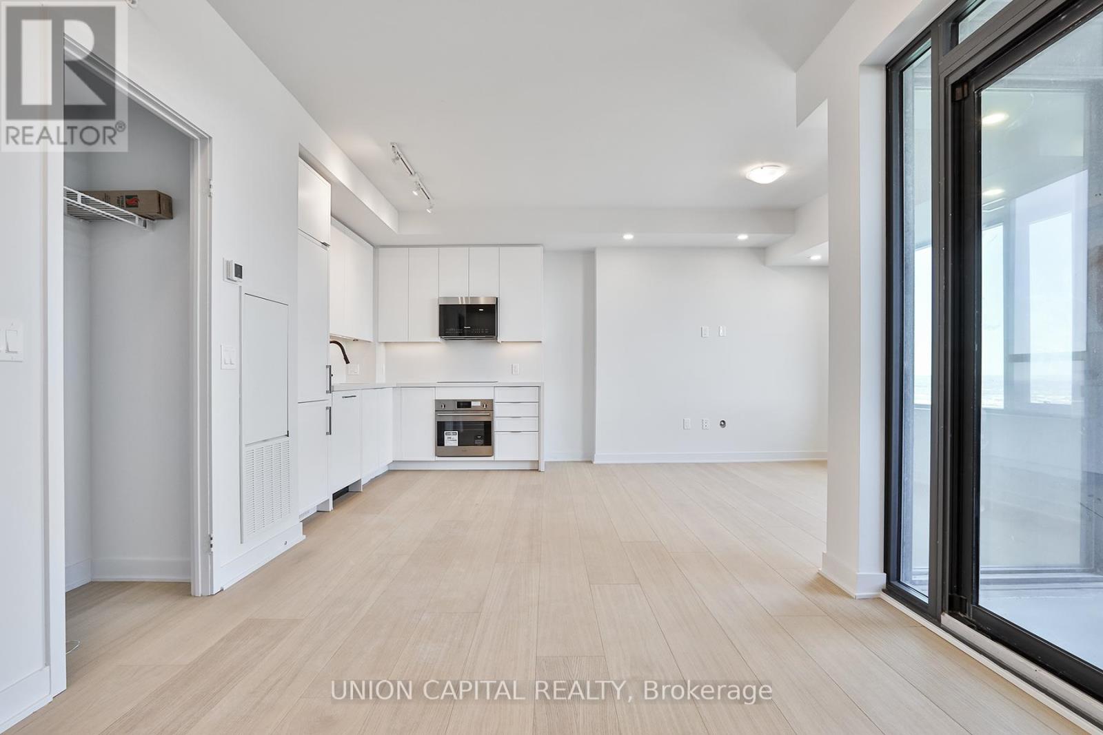 A spacious, empty room with wooden floors and white walls.