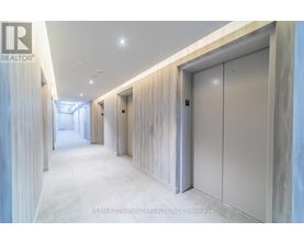 A long hallway with a white floor and walls, and a row of white doors on the right side.