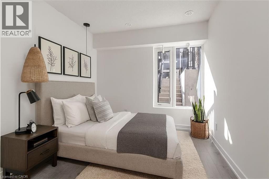 A bedroom with a bed, nightstand, and a window with a view of a city.