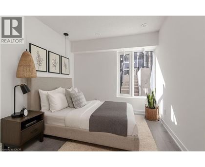 A bedroom with a bed, nightstand, and a window with a view of a city.
