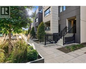A sunny day at a modern apartment complex with a REALTOR® sign.