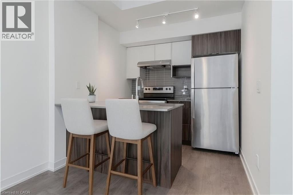 A modern kitchen with white chairs and a stainless steel refrigerator.
