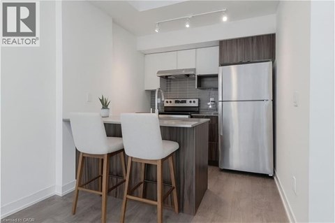 A modern kitchen with white chairs and a stainless steel refrigerator.