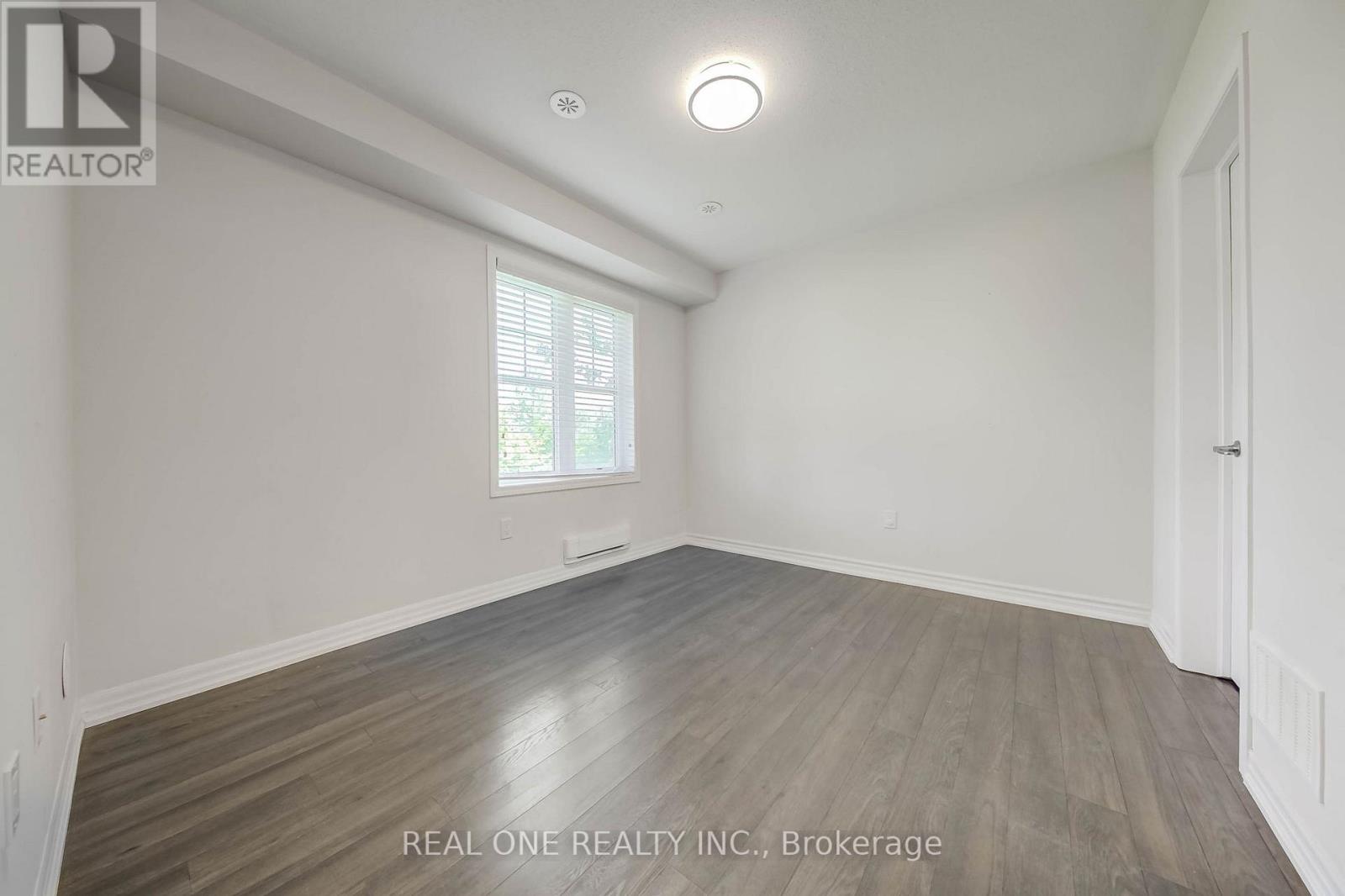A spacious room with wooden flooring and a window.
