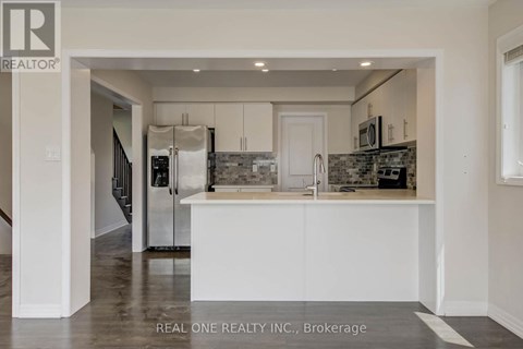 A kitchen with white cabinets and a black and white tiled backsplash.