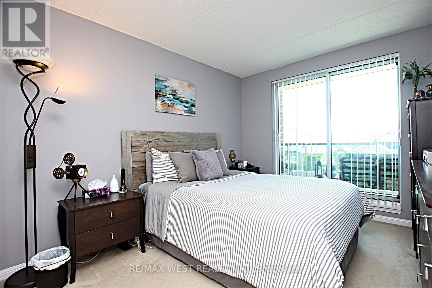 A bedroom with a bed, nightstand, and a window with blinds.