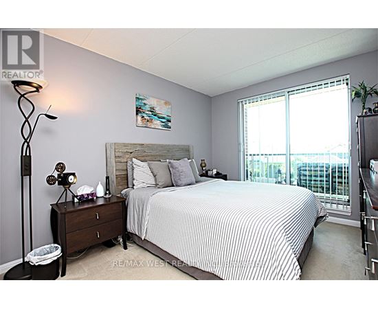 A bedroom with a bed, nightstand, and a window with blinds.