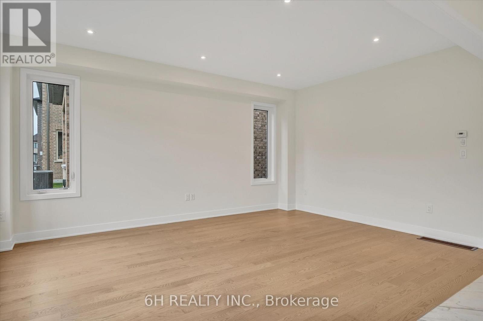 A spacious room with wooden flooring and white walls, ready for brokerage.