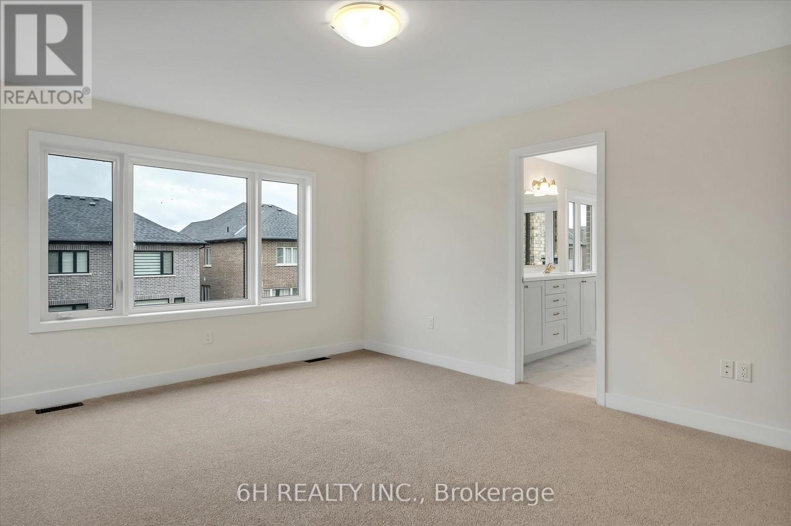 A realtor photo of a bedroom with a carpeted floor and a view of other houses through the window.