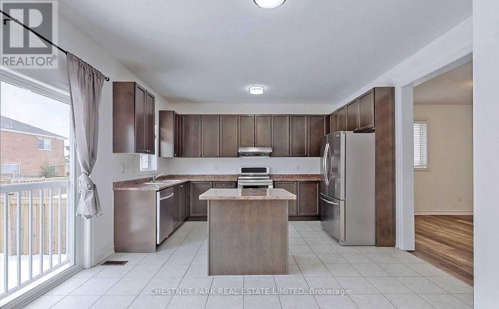 A kitchen with a refrigerator, sink, and cabinets.