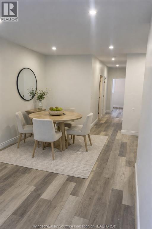 A dining room with a round mirror and a table with chairs.