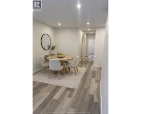 A dining room with a round mirror and a table with chairs.