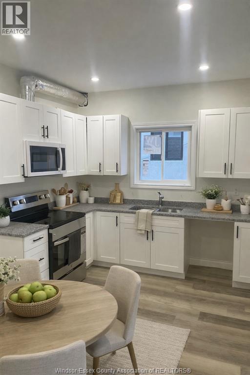 A kitchen with white cabinets and a wooden table with a bowl of fruit on it.