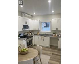 A kitchen with white cabinets and a wooden table with a bowl of fruit on it.