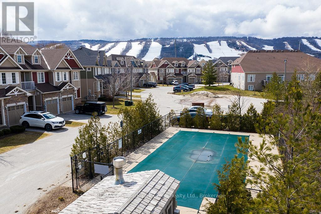 A pool surrounded by a fence and houses with mountains in the background.