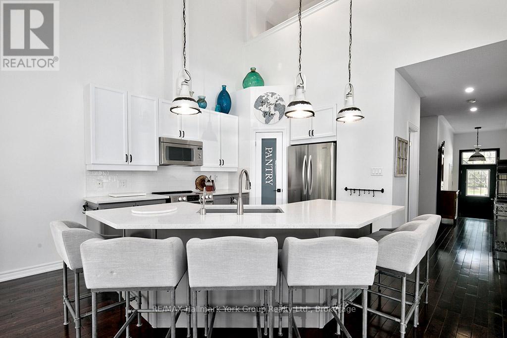 A modern kitchen with white chairs and a white table.