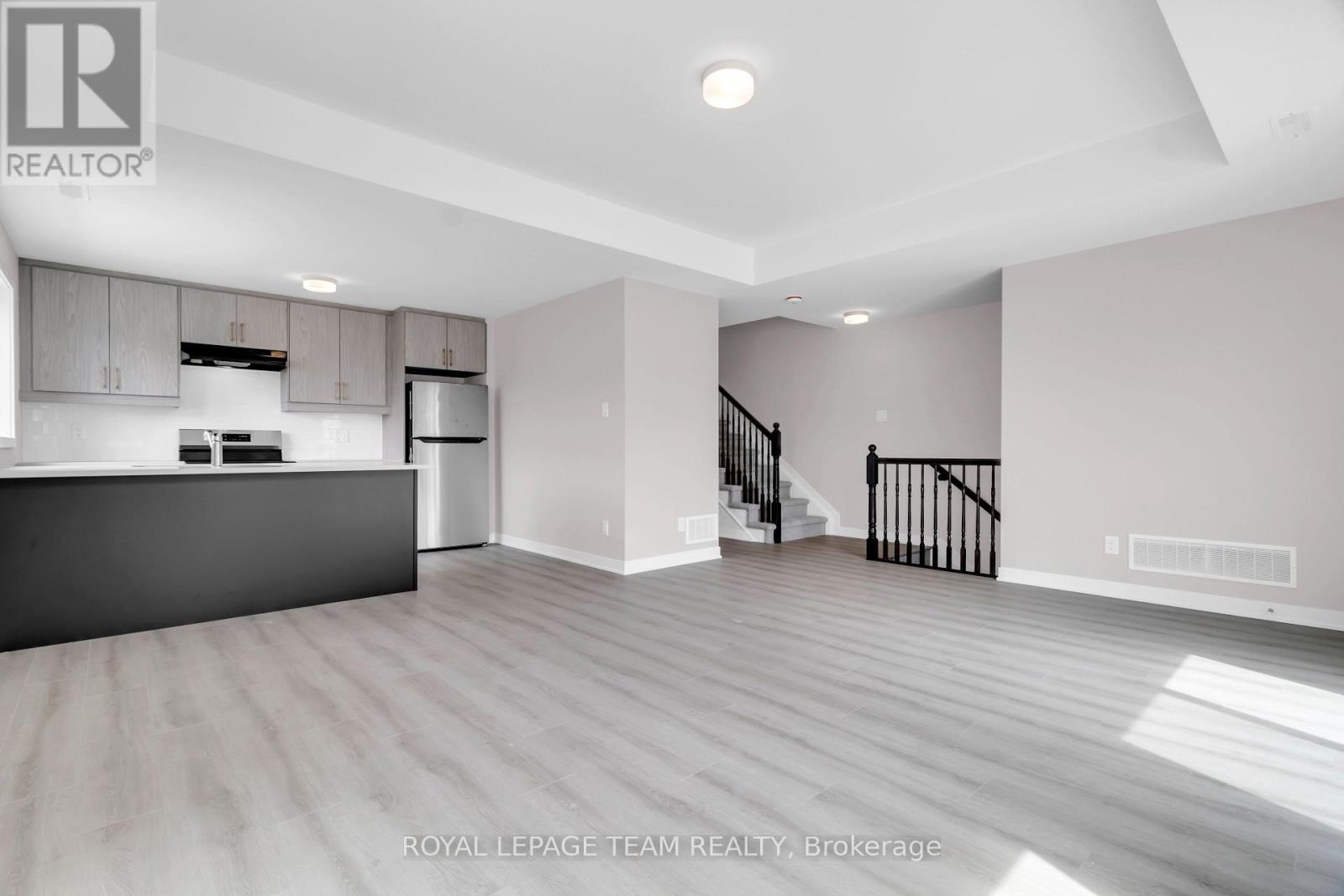 A spacious, empty room with a staircase leading to the upper level.