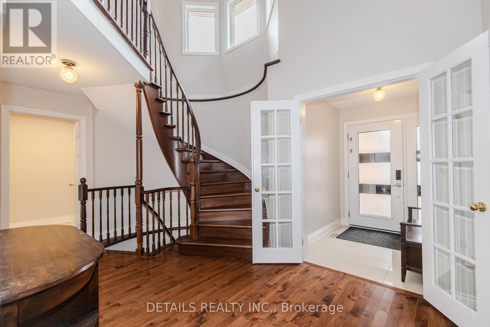 A spacious room with a staircase and a doorway leading to another room.