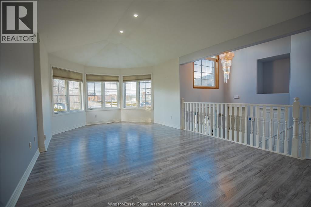 A large, empty room with wooden floors and a white railing.