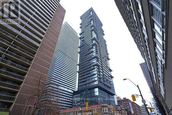 A tall building with a glass facade stands in the middle of a city street.