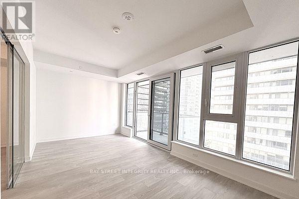 A spacious room with large windows and a wooden floor.