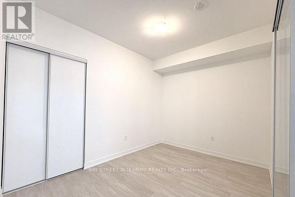 A white bedroom with a sliding door and a wooden floor.