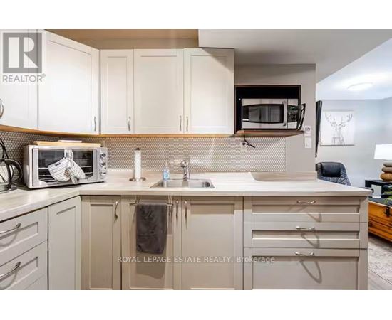 A kitchen with white cabinets and a microwave on the counter.