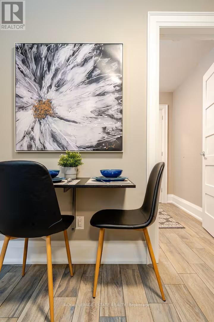 A dining room with a large painting on the wall and a small table with two chairs.