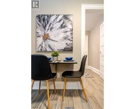 A dining room with a large painting on the wall and a small table with two chairs.
