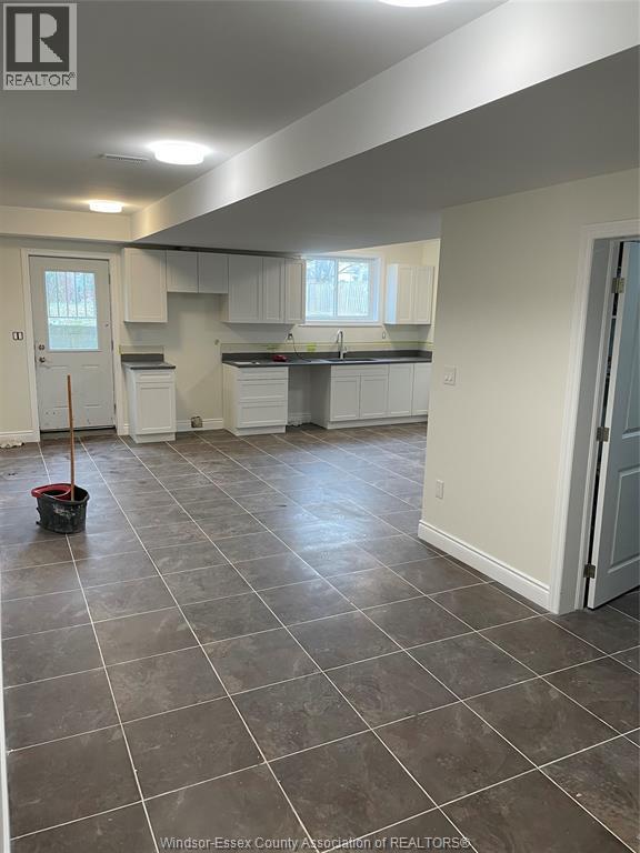 A kitchen and living room with tile flooring and white walls.