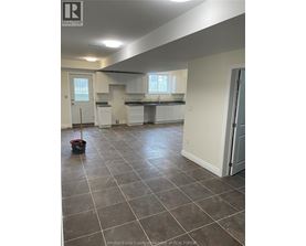 A kitchen and living room with tile flooring and white walls.