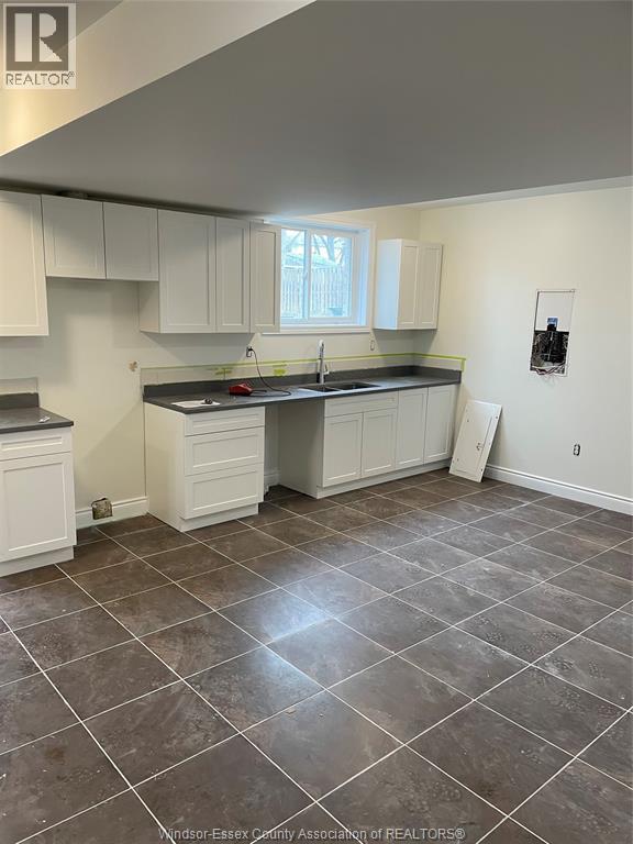 A kitchen with white cabinets and a tile floor.