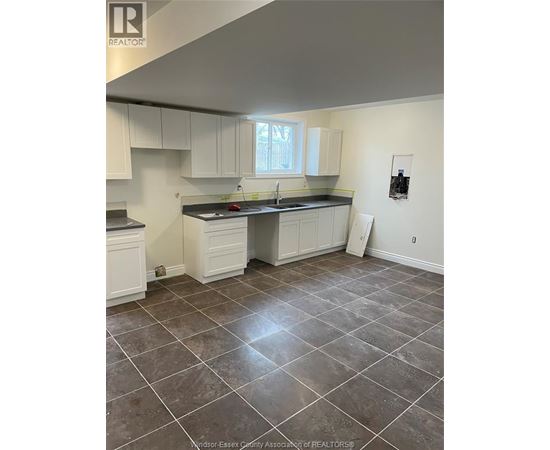 A kitchen with white cabinets and a tile floor.