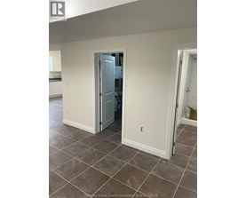 A room with a tiled floor and a doorway leading to another room.