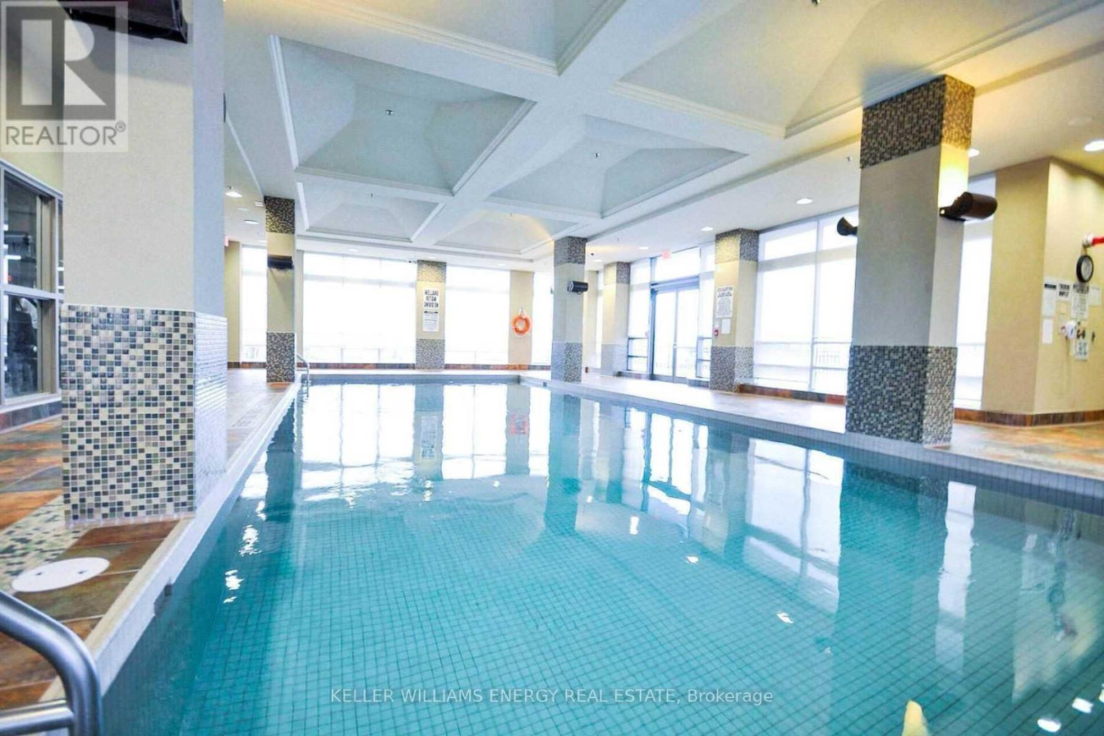 A large indoor swimming pool with a tiled edge and a metal hand rail.