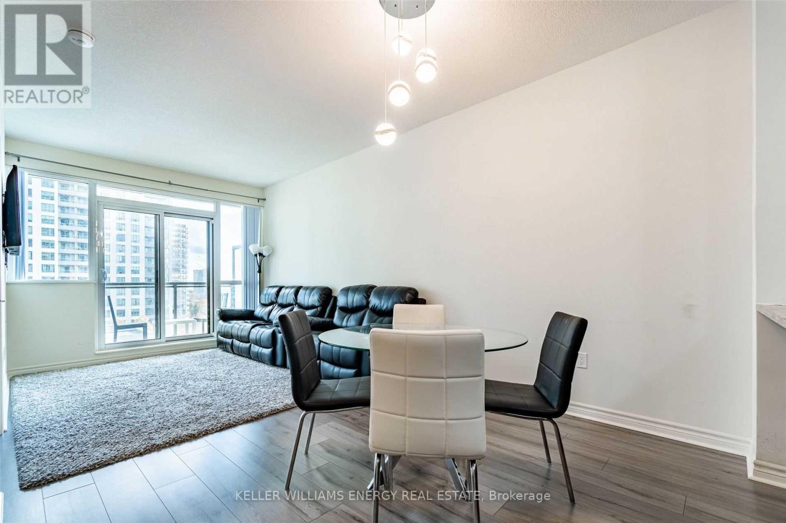 A living room with a black leather couch and a white chair.