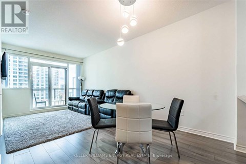 A living room with a black leather couch and a white chair.
