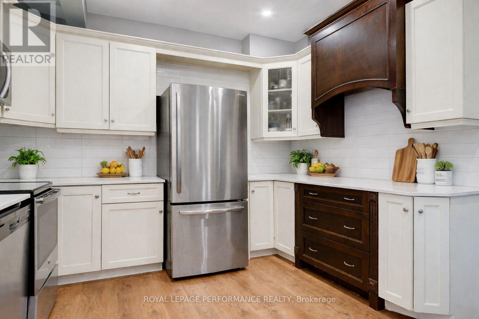A kitchen with white cabinets and a stainless steel refrigerator.
