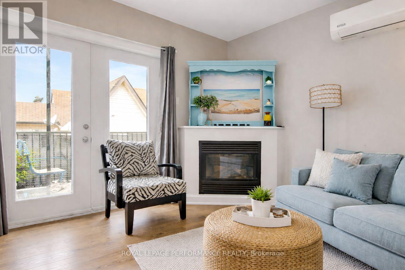 A living room with a fireplace and a painting of a beach scene on the wall.