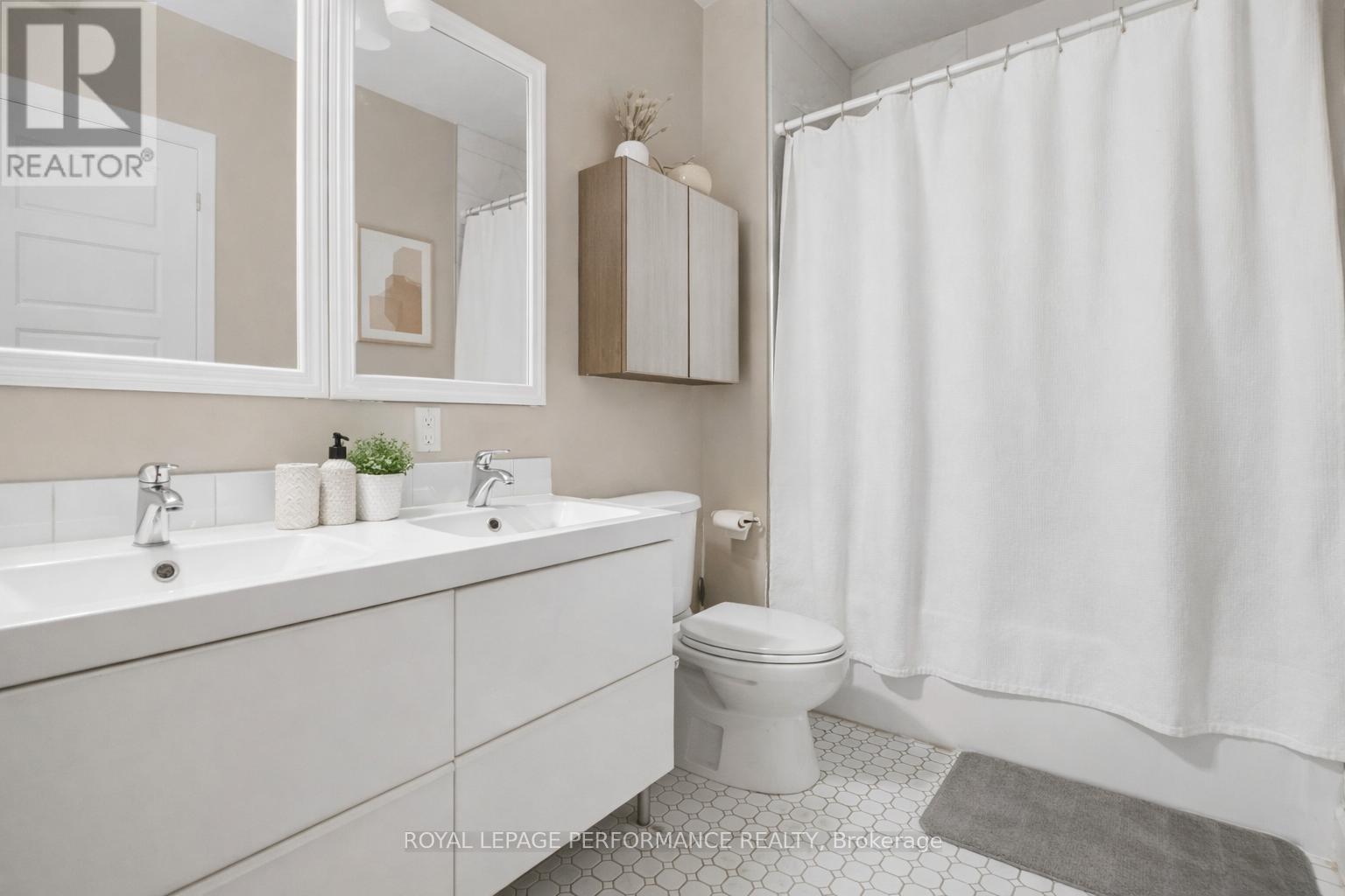 A white bathroom with a toilet, sink, and shower curtain.