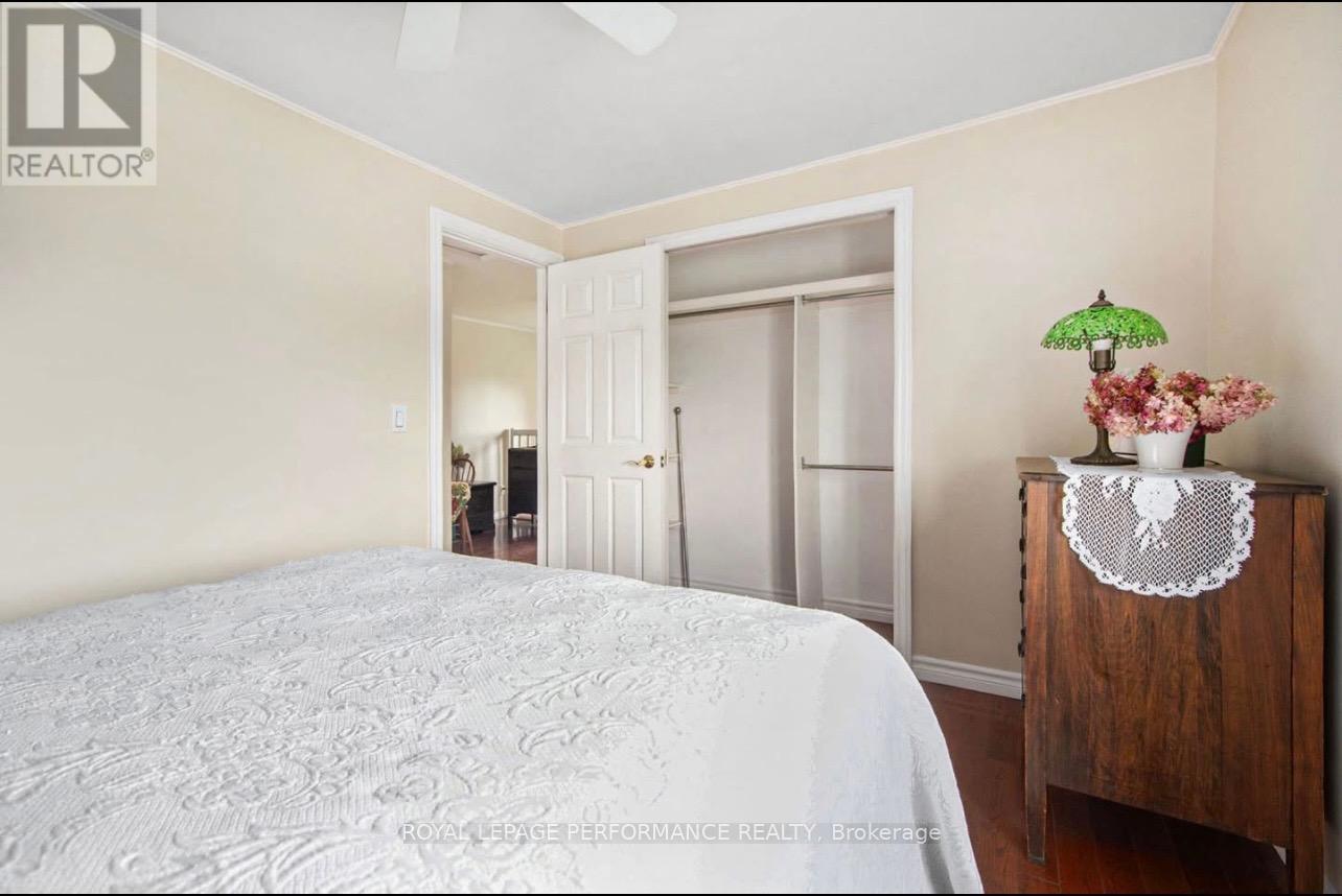 A bedroom with a bed, a nightstand with a plant, and a doorway leading to another room.
